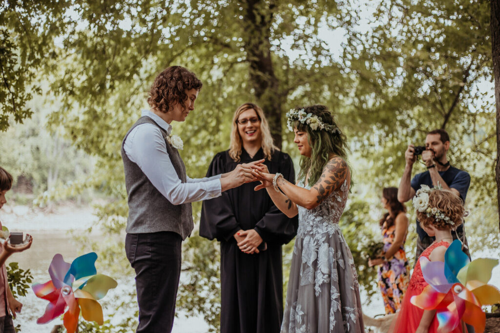 Exchanging of the rings at a wedding ceremony with an officiant behind the couple.
