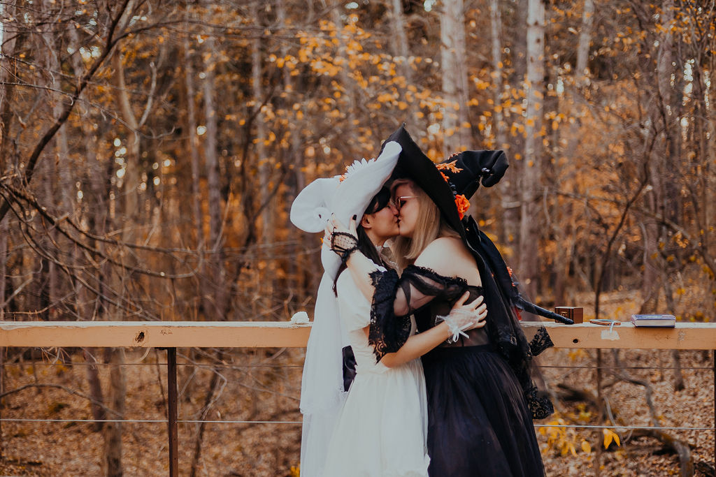 A couple kissing, dressed in Halloween-themed attire during their fall elopement.