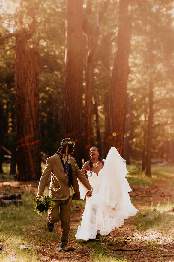 Couple running and laughing through a forest during their elopement.
