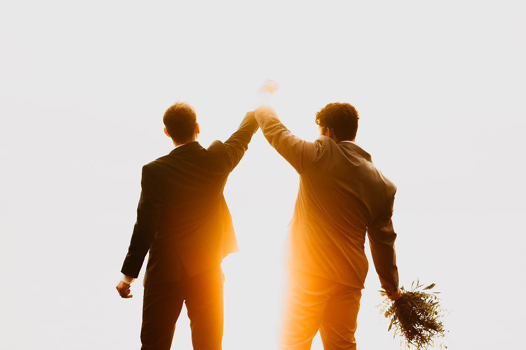 Couple holding their hands in the air to symbolize a successful elopement.