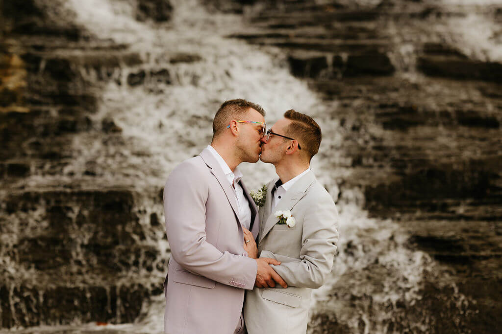 Couple kissing in front of waterfall during their elopement.