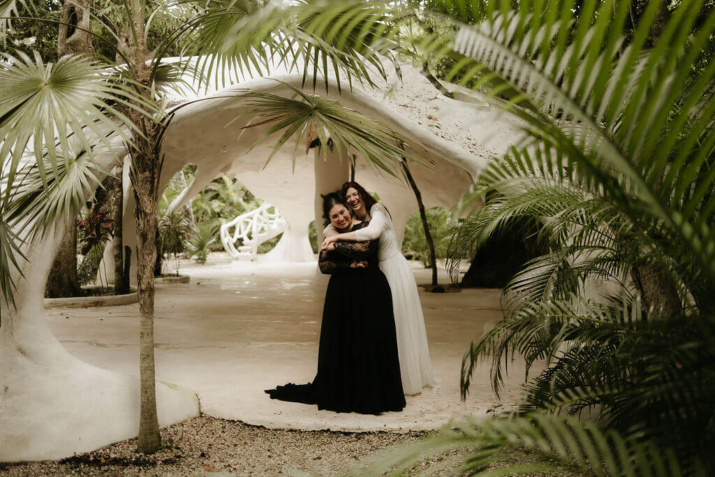 Destination wedding in Mexico. The photo is framed with palm trees with the couple embracing.